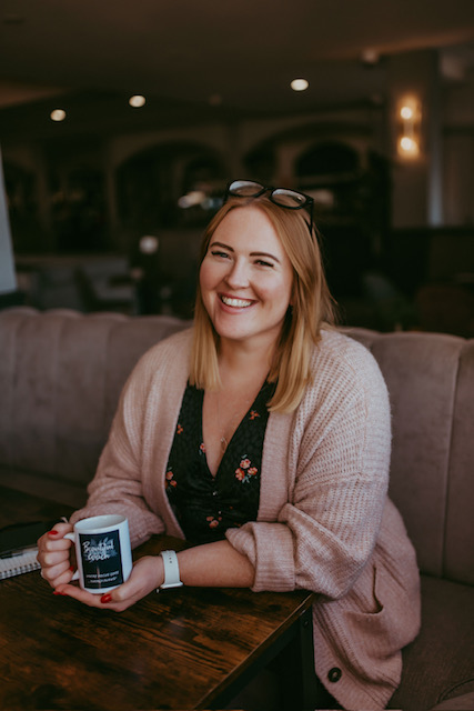 Hannah Murray, Mental Health & Wellbeing coach smiling with a branded mug in her hands